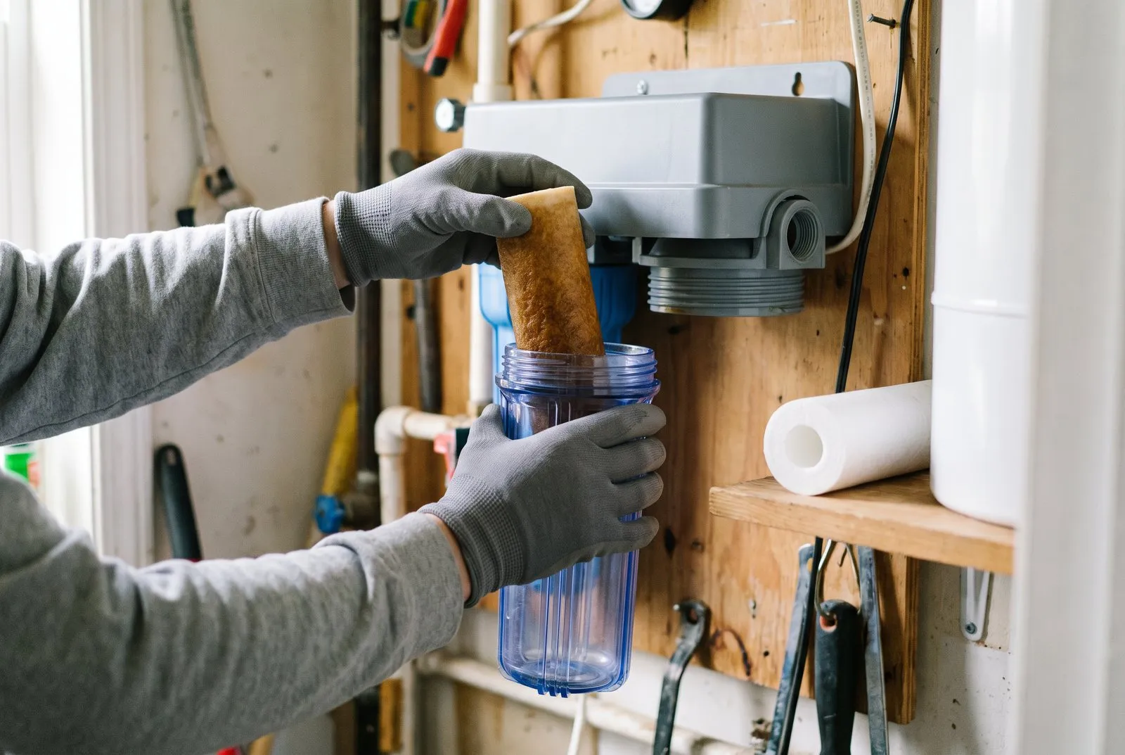 Gloved hands changing a filter cartridge in a filter housing, with no logos visible.