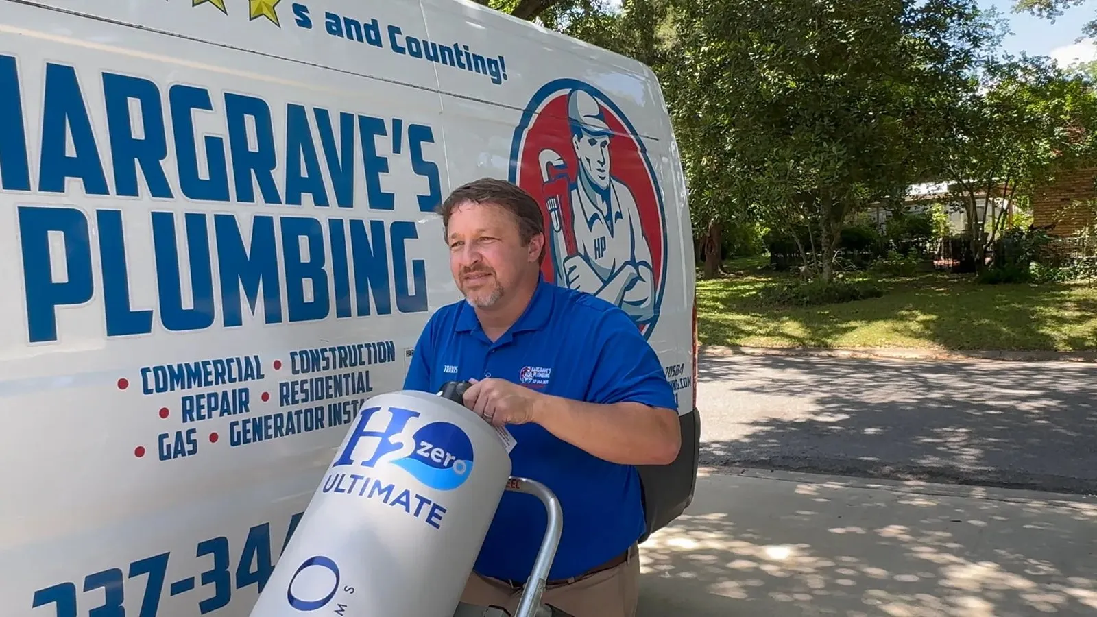 Travis Hargrave bringing a whole-home filtration tank to an install, beside the Hargrave's Plumbing van